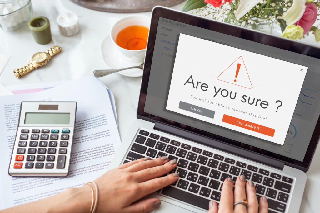 Laptop screen displaying a critical deletion warning popup, illustrating common mistakes and anxiety when managing website pages manually.