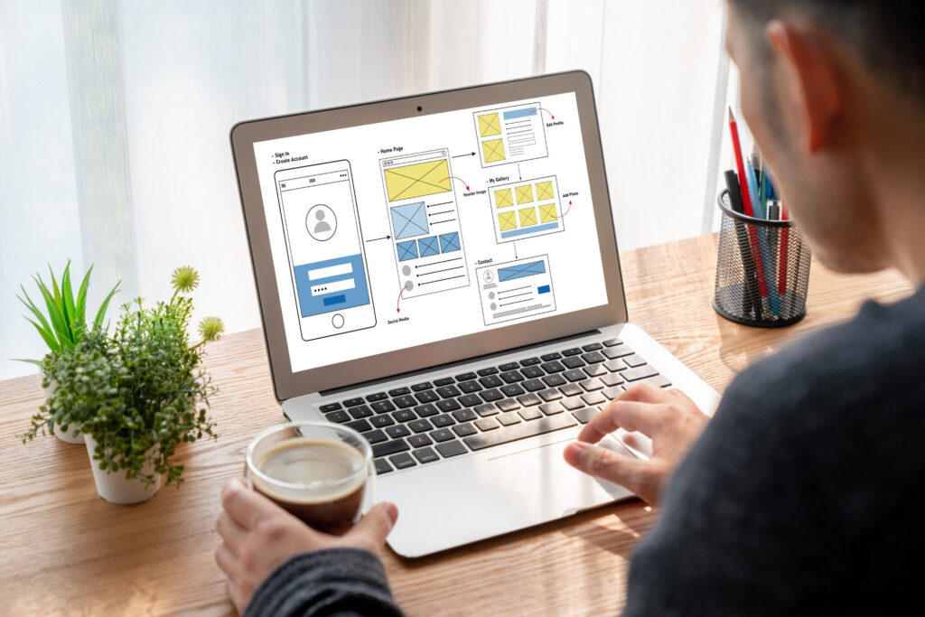 Person working on a laptop displaying a website structure wireframe, illustrating the planning process for adding pages on website builders.